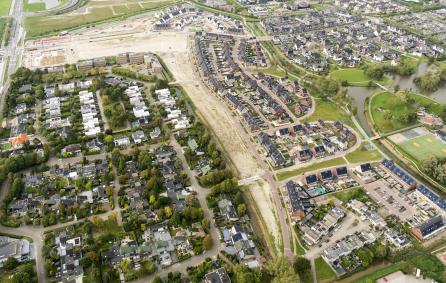 Luchtfoto met bestaande straten en een grote plek grond waar gebouwd gaat worden.