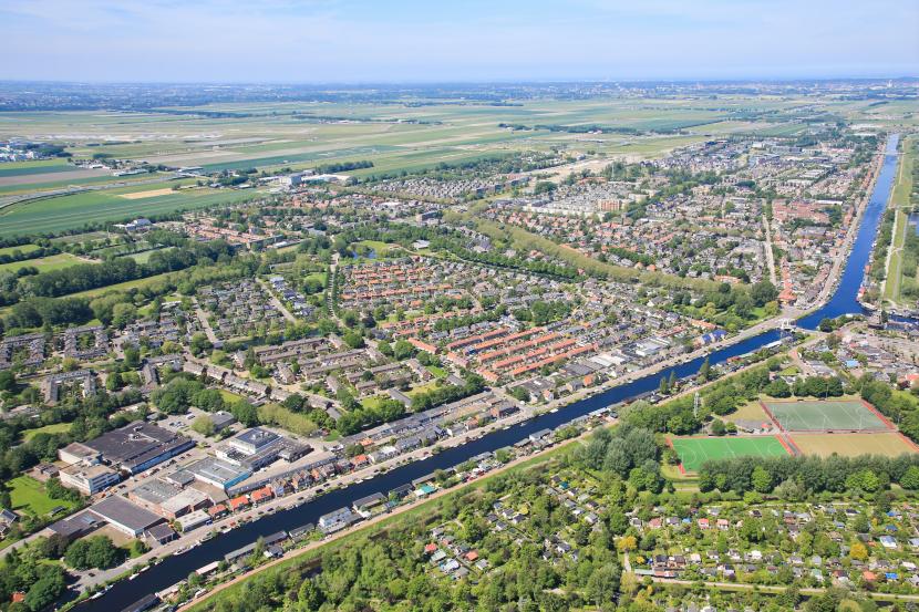 Luchtfoto van Badhoevedorp met de Ringvaart, een brug, een bedrijventerrein  en woningen
